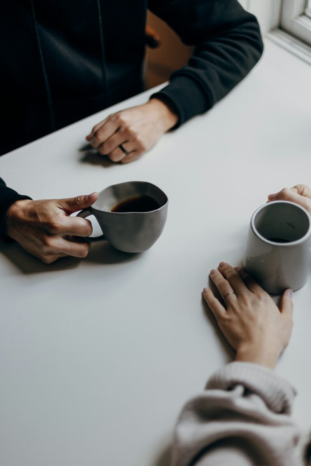 Two people at a table with coffee, hands not connected